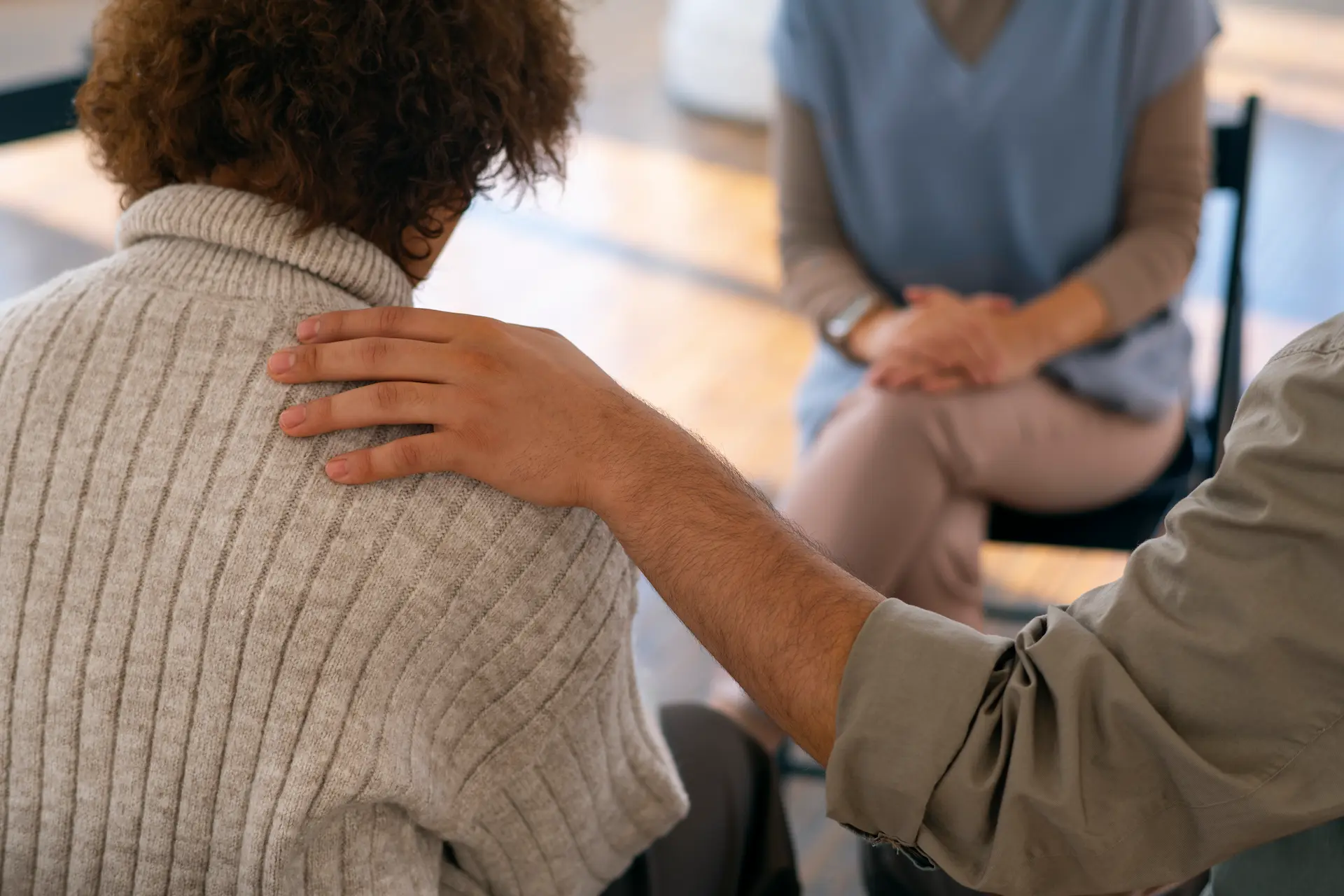 Therapist placing a supportive hand on a client's shoulder during a group session
